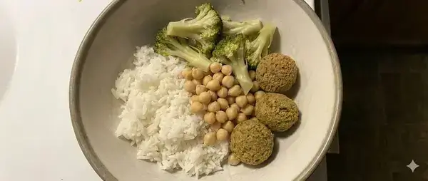 A bland and depressing vegan meal of plain rice, dry chickpeas, unseasoned broccoli, and store-bought falafel